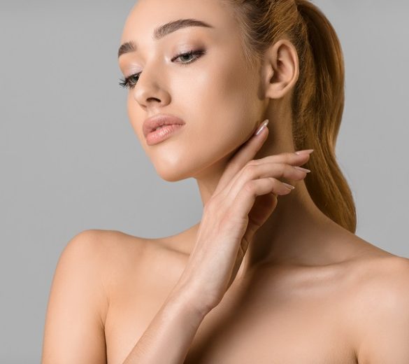 Beauty portrait. Young woman with natural make-up posing over grey studio background